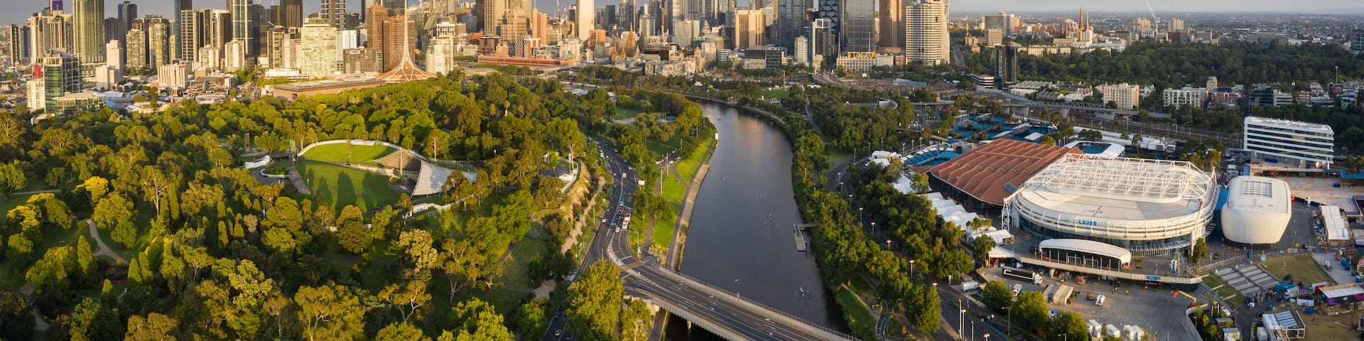 A city skyline with modern skyscrapers, a river, and a stadium.