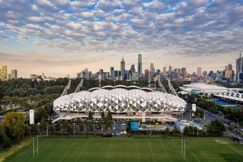 A stadium with a unique geodesic dome structure surrounded by a city skyline and a green field.