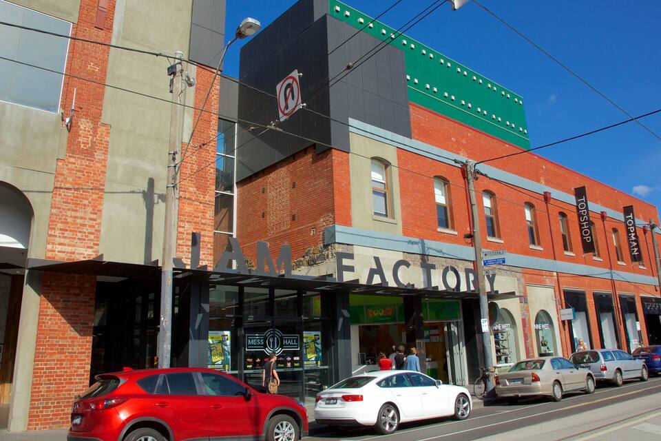 Una strada con un edificio che riporta le scritte 'FACTORY' e 'TOPSHOP'.