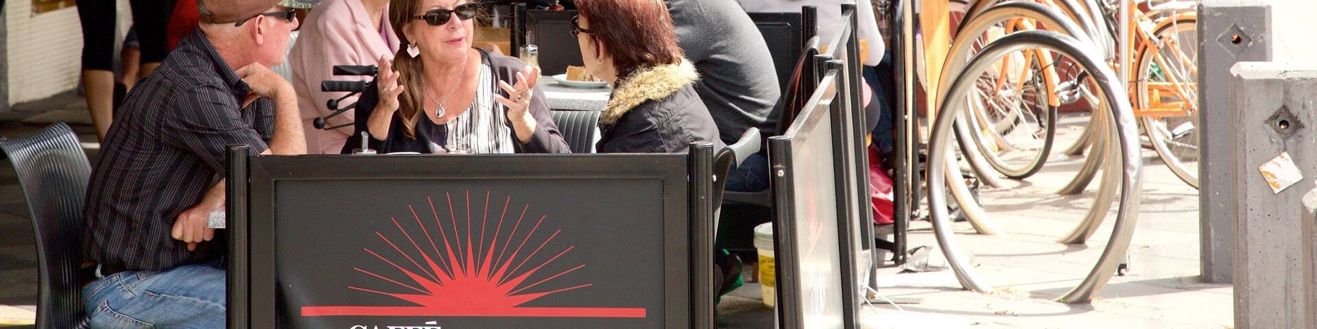 Acland Street das einen Café-Szenerien und Essen im Freien sowie große Menschengruppe