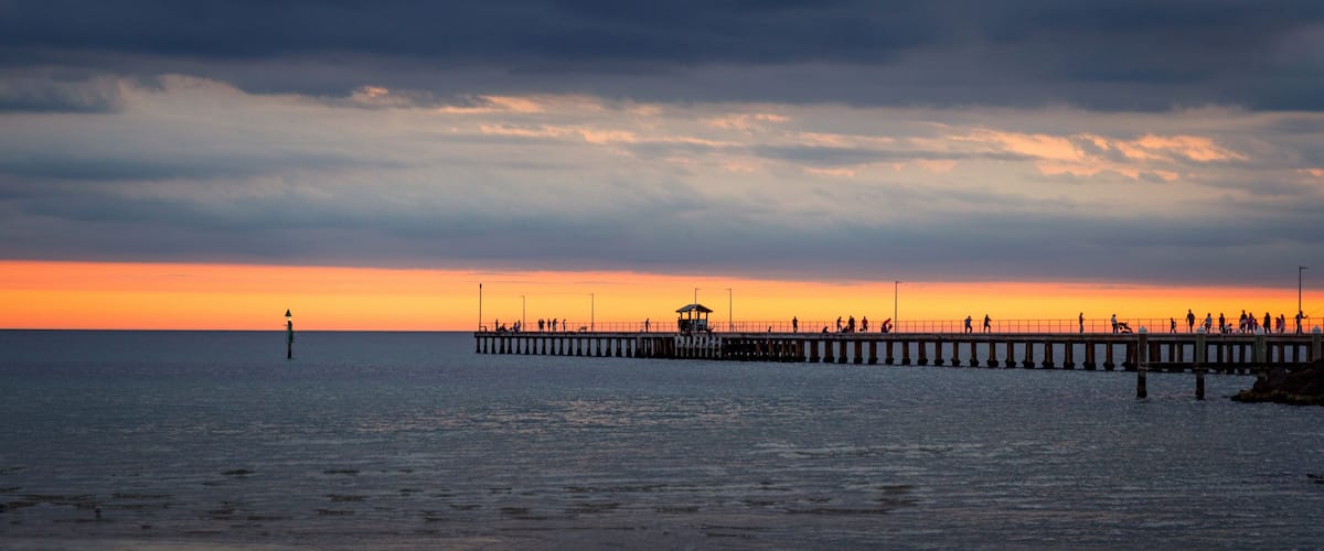 Mordialloc pier near Melbourne Australia at sunset with golden sky and clouds .