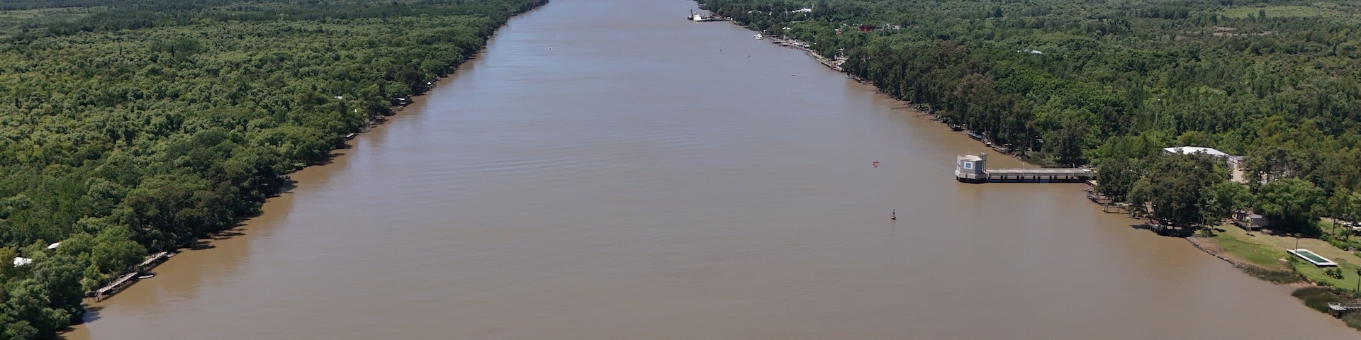 río paraná con árboles en la costa y barcos navegando, atardecer