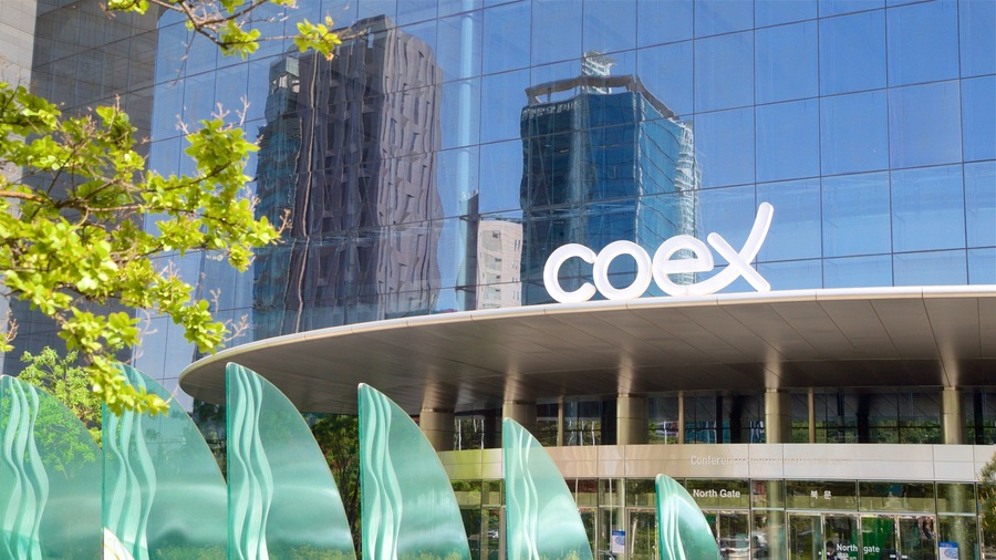 A modern building with a glass facade reflecting nearby skyscrapers.
