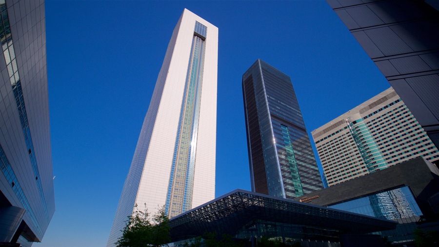 A cluster of modern skyscrapers with glass facades and geometric shapes, under a clear blue sky.