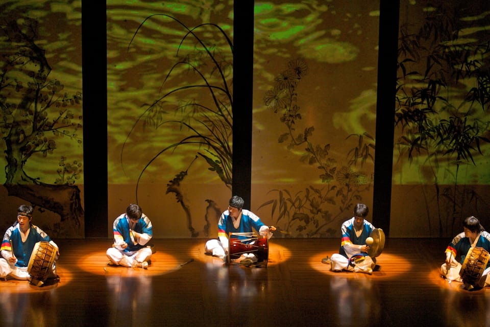 A stage with four musicians performing traditional instruments.