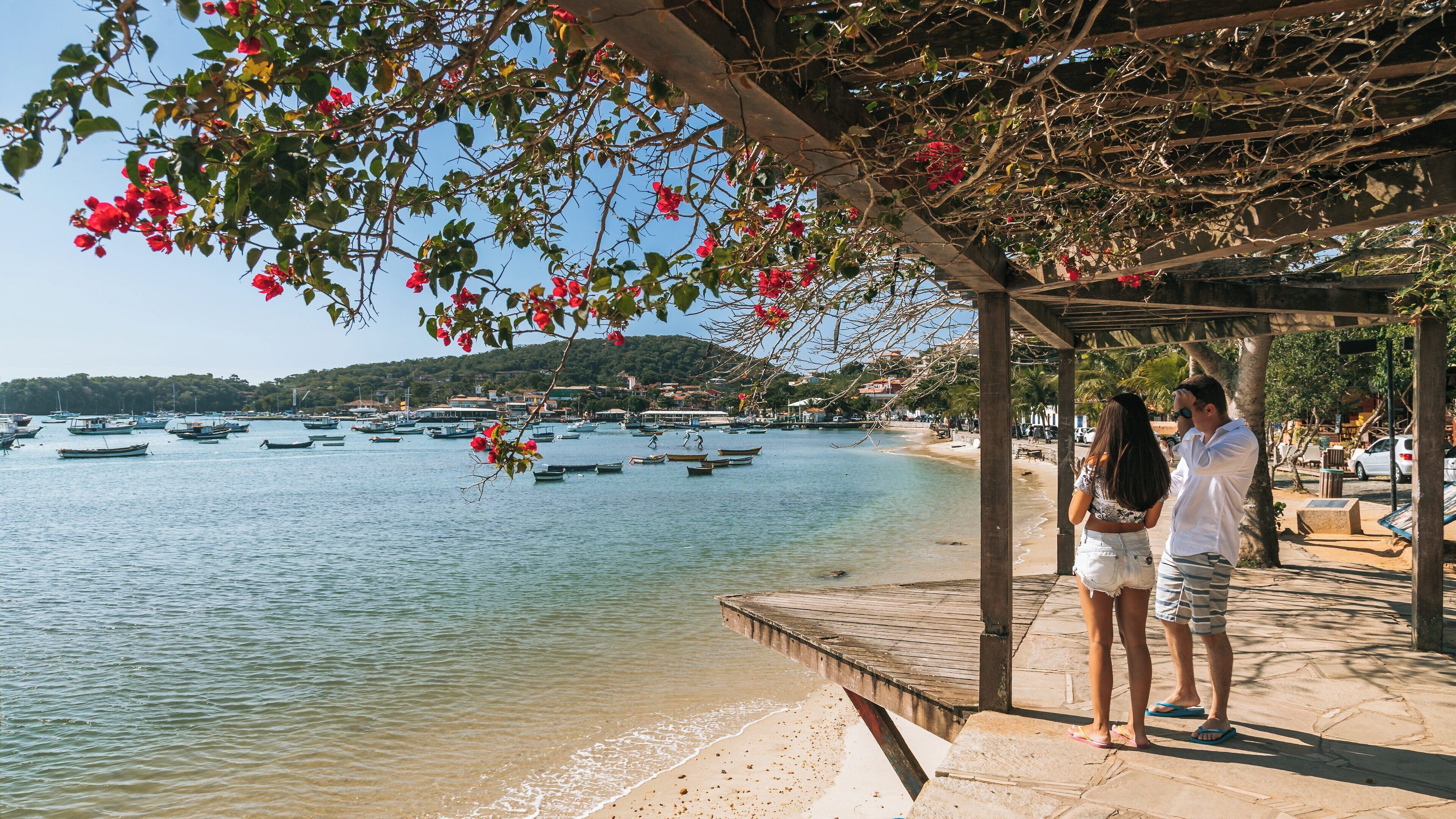 Stunning view of Armacao Beach in Buzios, Brazil, showcasing couples enjoying the serene shoreline and vibrant nature