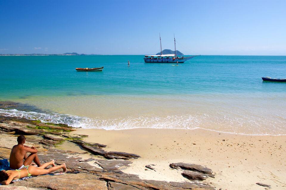 A beach with clear turquoise water, rocky shore, and several boats.