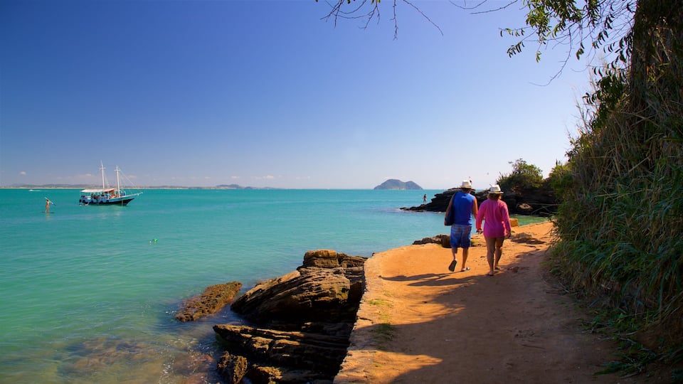 Uma trilha costeira com águas turquesa cristalinas, uma costa rochosa e um barco ao longe.