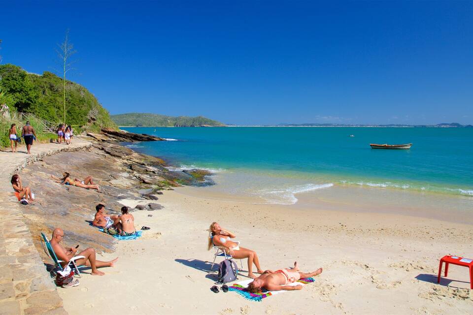 A sunny beach with people sunbathing and relaxing on the sand.