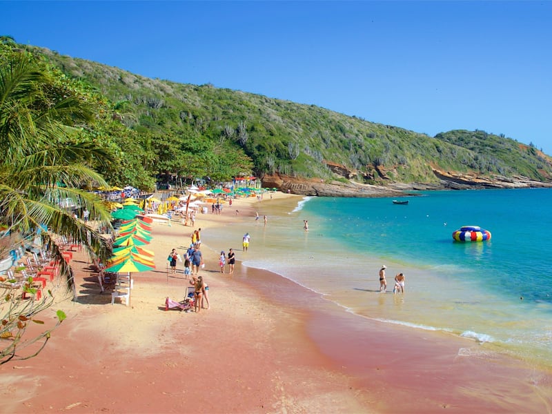 A beach with palm trees, umbrellas, and people.