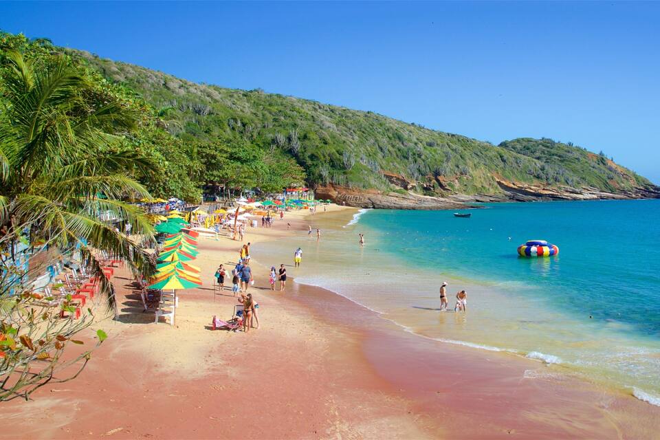 A beach with palm trees, umbrellas, and people.
