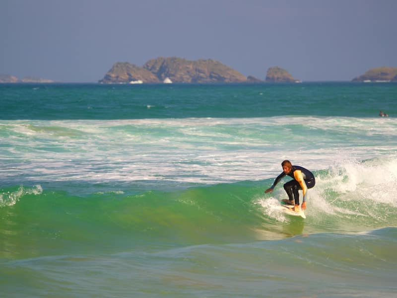 A surfer riding a wave with distant rocky islands.