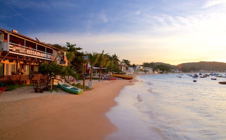 A beach with boats, a restaurant, and palm trees.