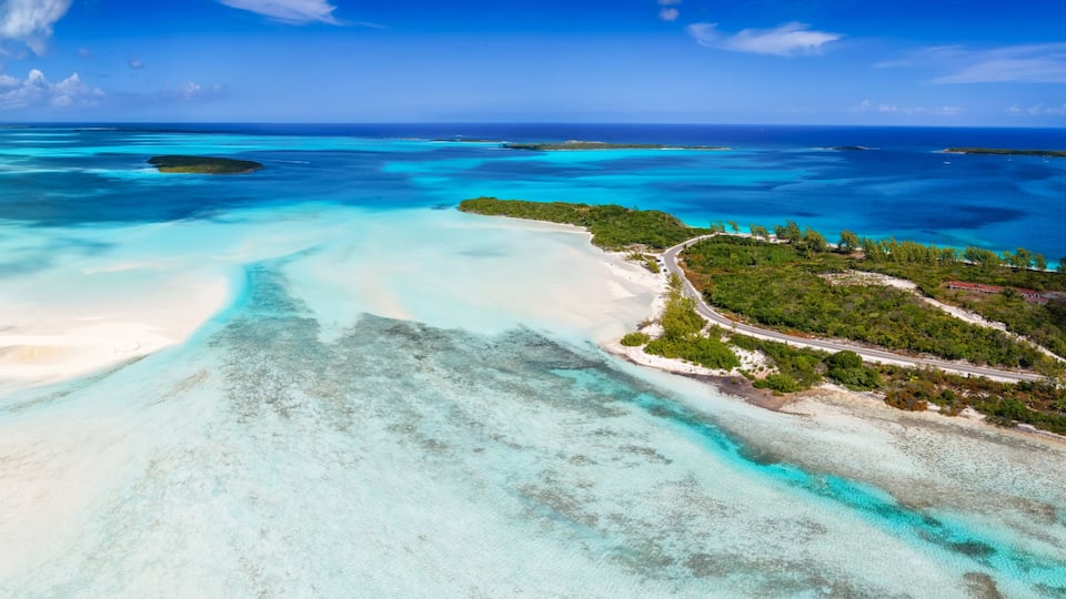 A tropical island with clear turquoise waters, white sandy beaches, and lush greenery.