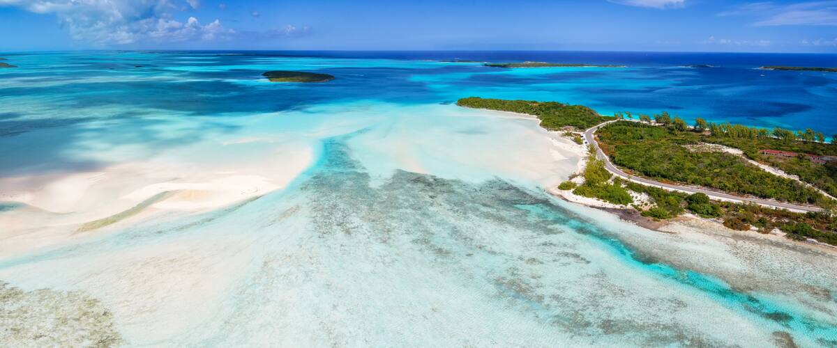A tropical island with clear turquoise waters, white sandy beaches, and lush greenery.