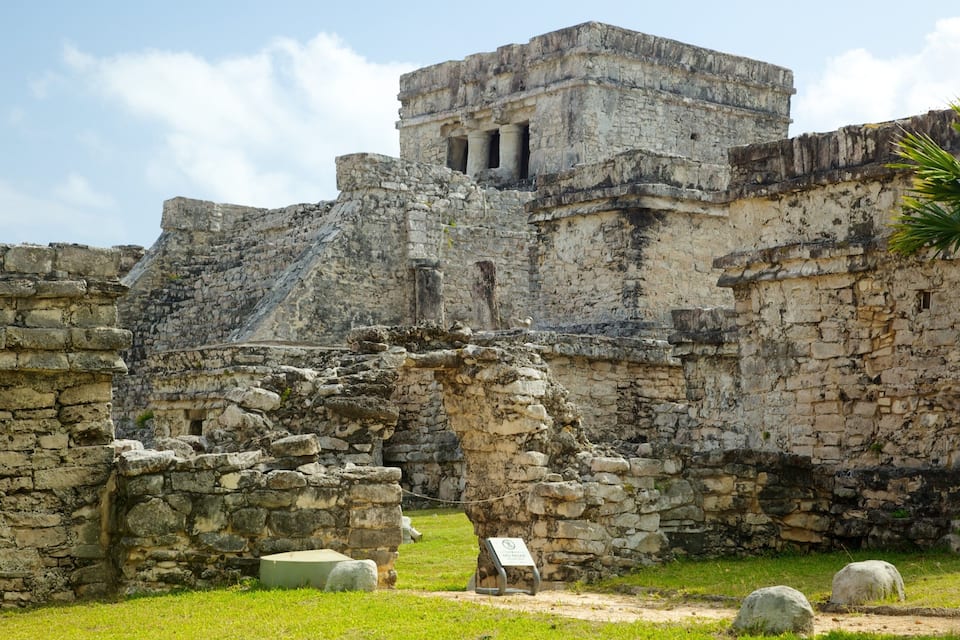Ancient stone ruins with a pyramid-like structure, a stone wall, and a sign indicating no photography.
