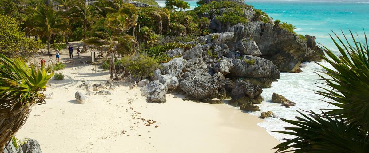 Ein Strand mit einem Felsen und einem kleinen Steingebäude.