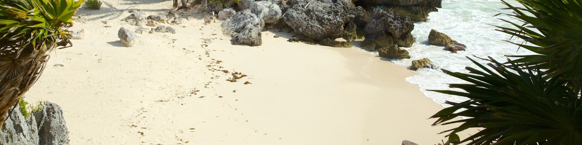 A beach with a rocky outcrop and a small stone structure.