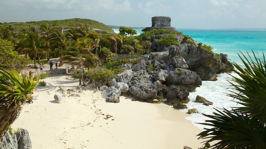 Une plage avec un promontoire rocheux et une petite construction en pierre.