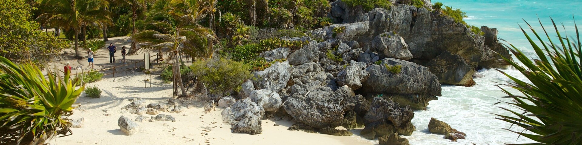 Una playa con un promontorio rocoso y una pequeña construcción de piedra.