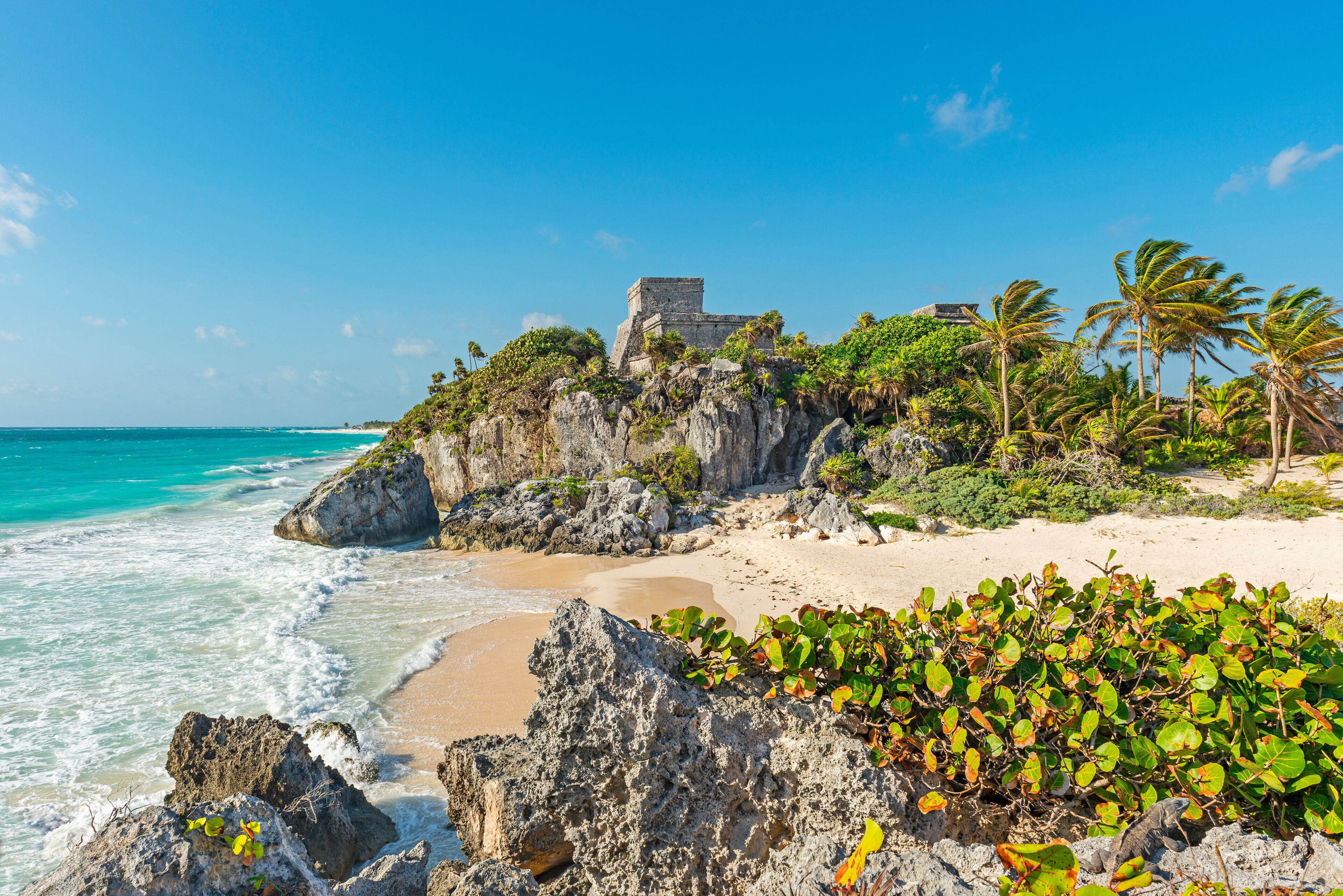 The Caribbean Sea with turquoise waters and white sand beach as a backdrop for the Tulum Maya ruins, Mexico.