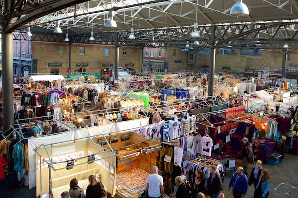 A bustling indoor market with various stalls selling clothes and accessories.