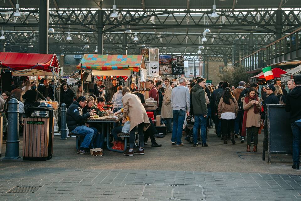 A busy outdoor market with people shopping and eating.