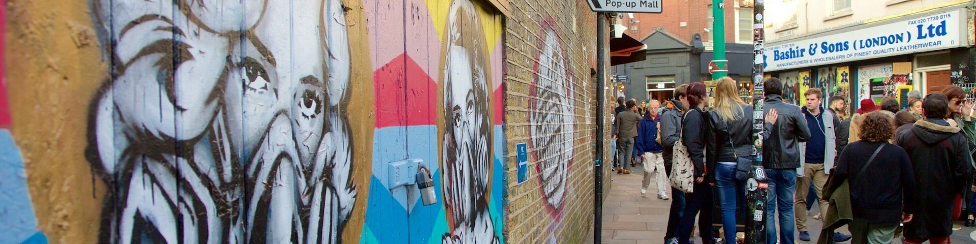Uma rua com um mural colorido, uma placa indicando o Boxpark Shoreditch Pop-up Mall e uma loja chamada Bashir & Sons (Londres) Ltd.