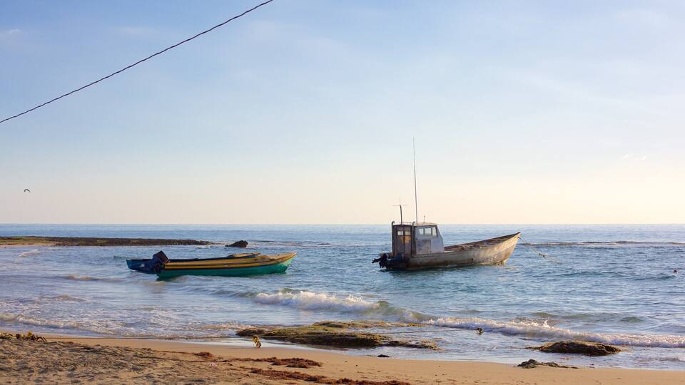 A beach with two boats, one yellow and one blue, and a rocky shoreline.