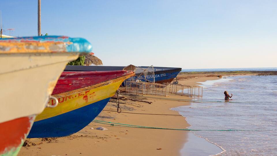 Colorful boats on a sandy beach with a child playing in the water.