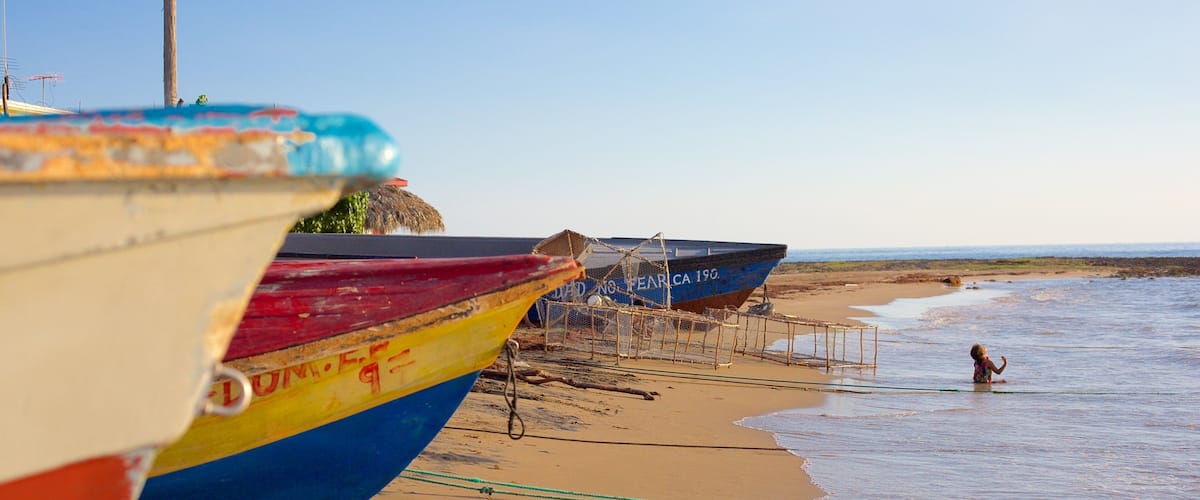 Colorful boats on a sandy beach with a child playing in the water.