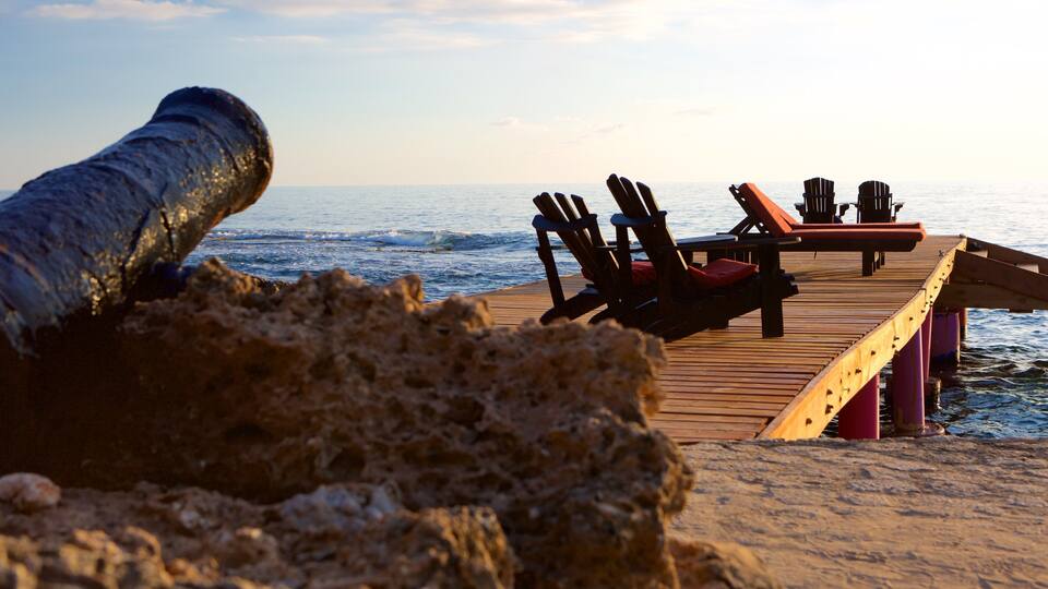 A wooden pier with lounge chairs extending over the ocean.