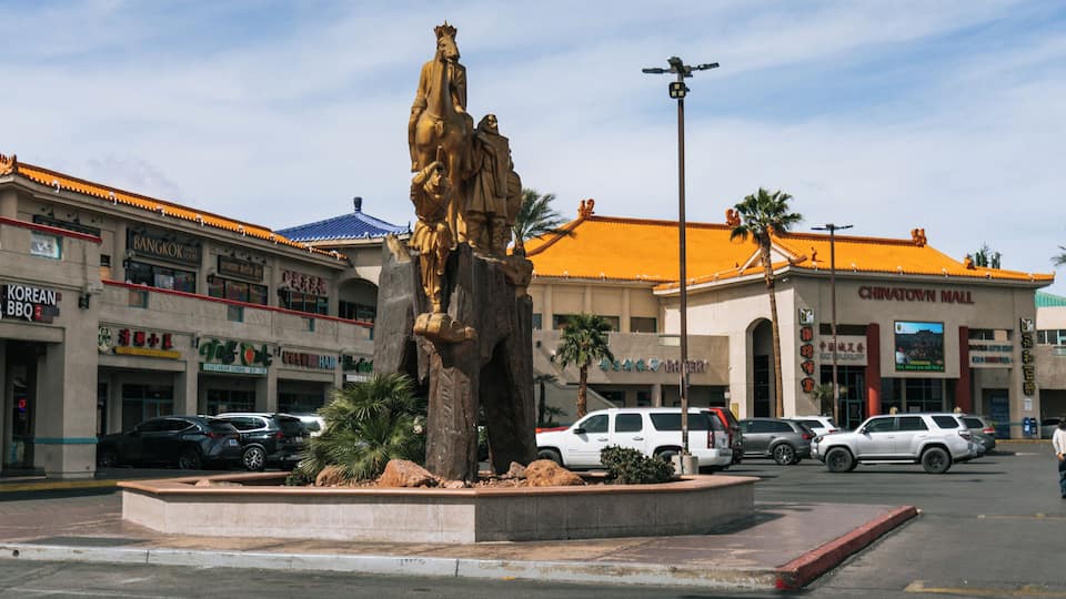 A statue in a plaza with a building labeled 'CHINATOWN MALL' in the background.
