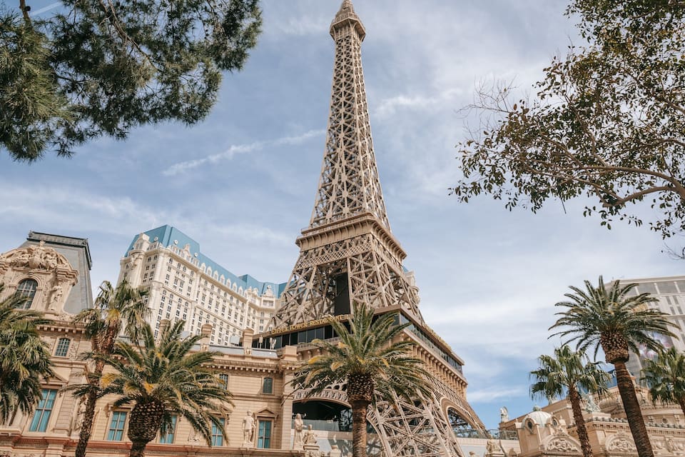 La Tour Eiffel, entourée de palmiers et d’immeubles modernes.