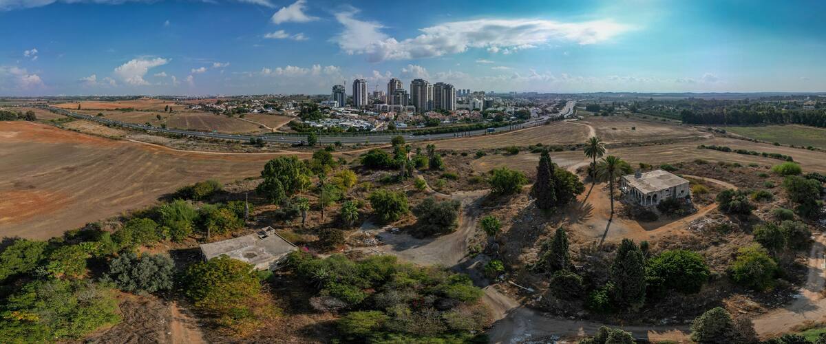 An aerial view of a city with high-rise buildings, a highway, and surrounding agricultural fields.