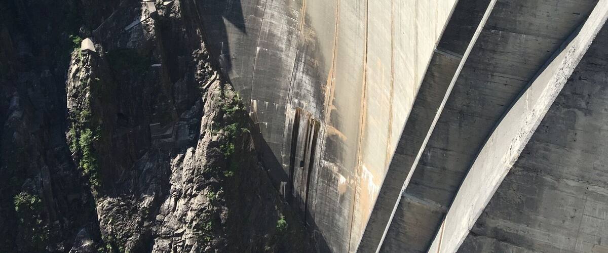 A large concrete dam with steep, terraced walls and a flat top.