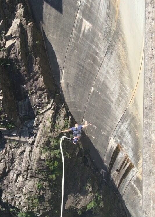 A person bungee jumping from a concrete structure.