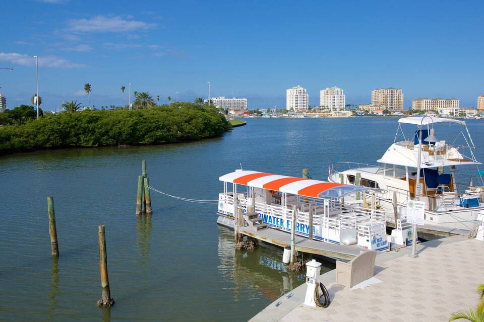 A river with a boat docked at a pier, surrounded by greenery and palm trees.