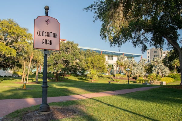 Placa indicando o Coachman Park, com um edifício moderno ao fundo.