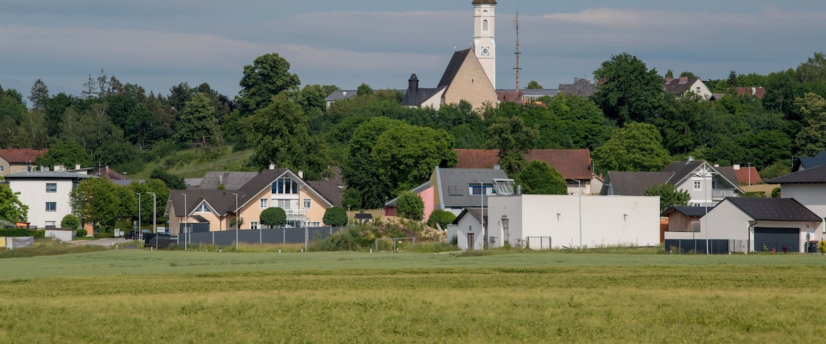 A church with a tall steeple, surrounded by houses and trees.