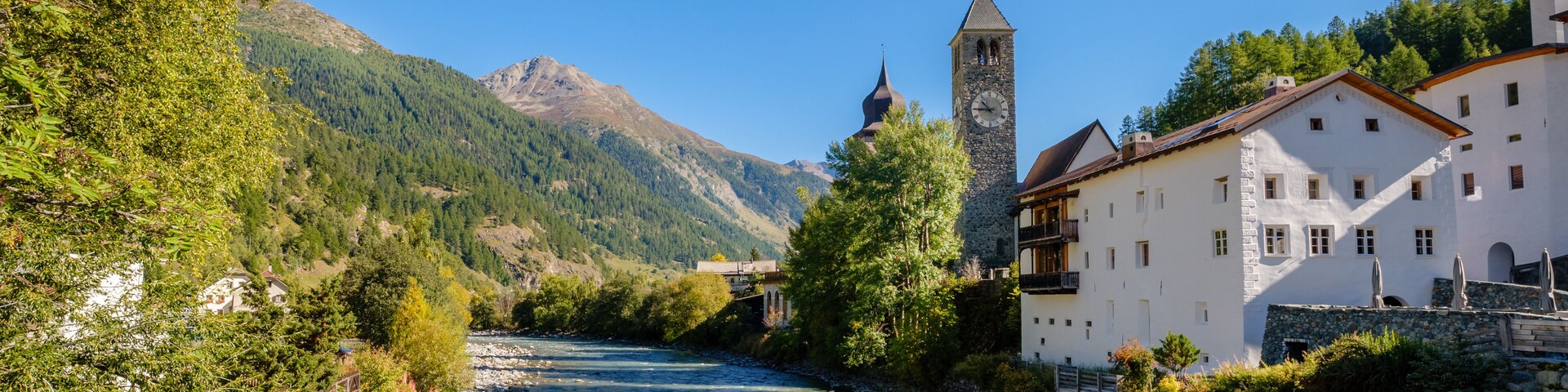 Un río serpentea por un pueblo con una torre de iglesia y edificios a lo largo de la orilla.
