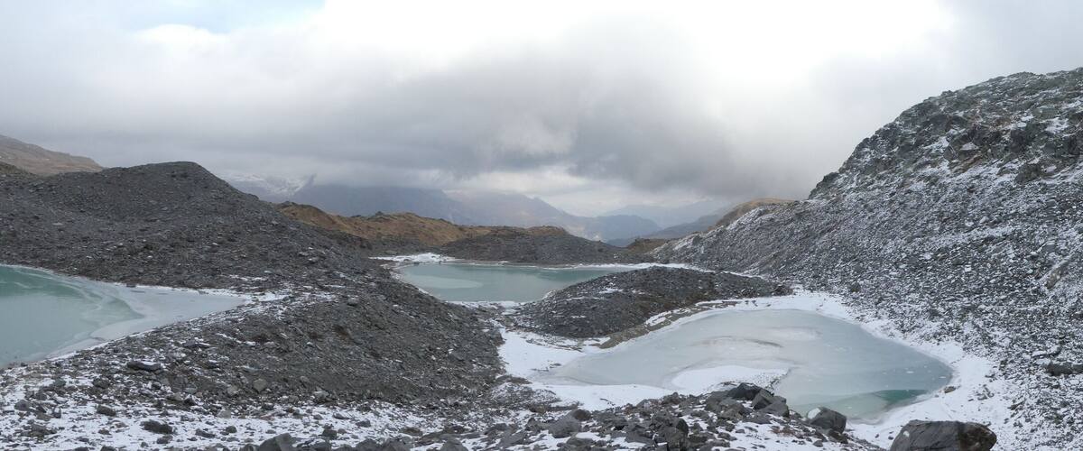 A mountainous landscape with snow-covered peaks and turquoise glacial lakes.