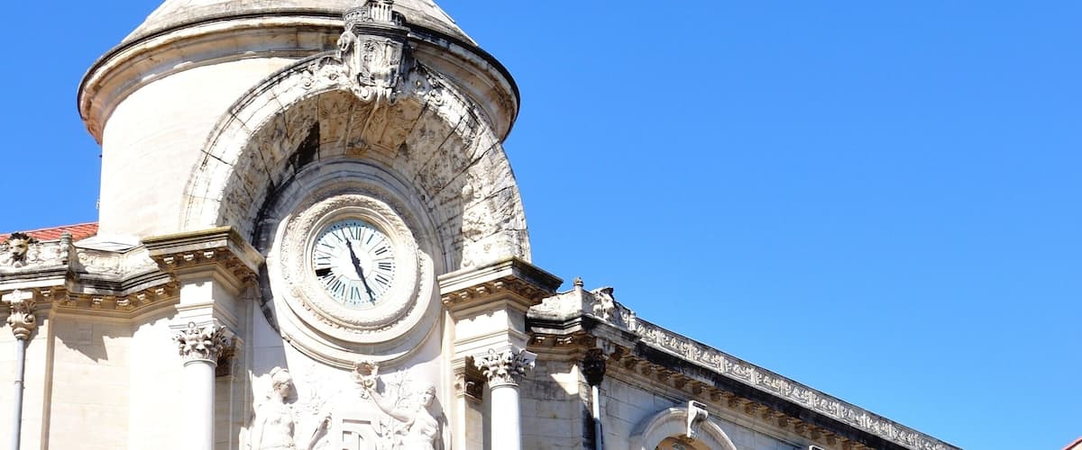 A historic building with a clock tower, detailed carvings, and a clear blue sky.