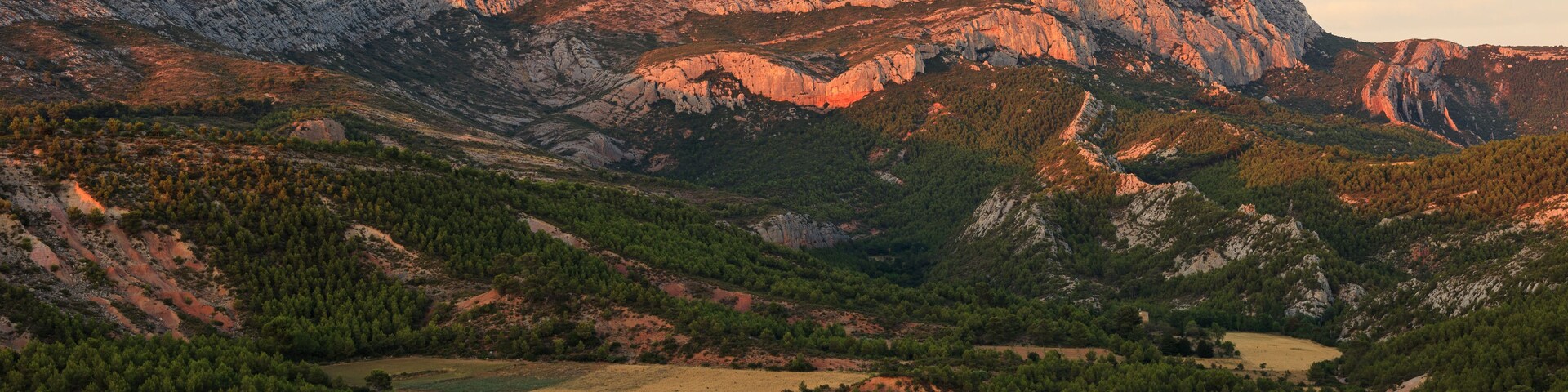 Sunset over Montagne Sainte-Victoire, near Aix-en-Provence, France. The warm evening light highlights the rugged limestone peaks, creating a stunning Provençal landscape.