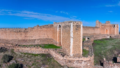 A large, ancient stone castle with multiple towers and walls, situated on a hill with sparse vegetation.