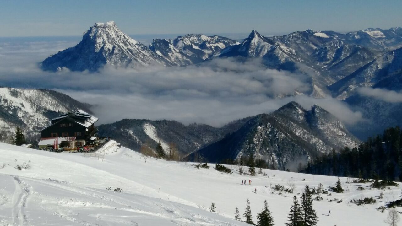 A snow-covered mountain landscape with a lodge and a prominent peak in the background.