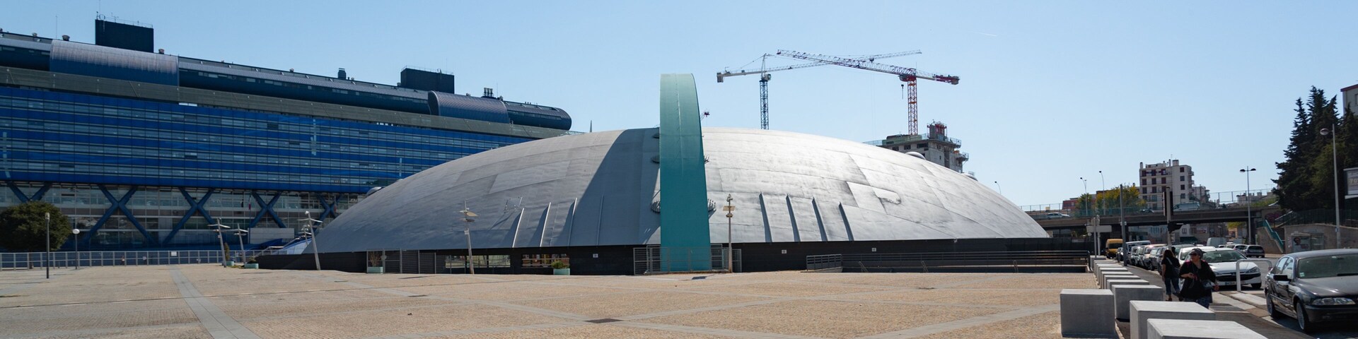 Un estadio moderno con una cúpula grande y un edificio azul al fondo.