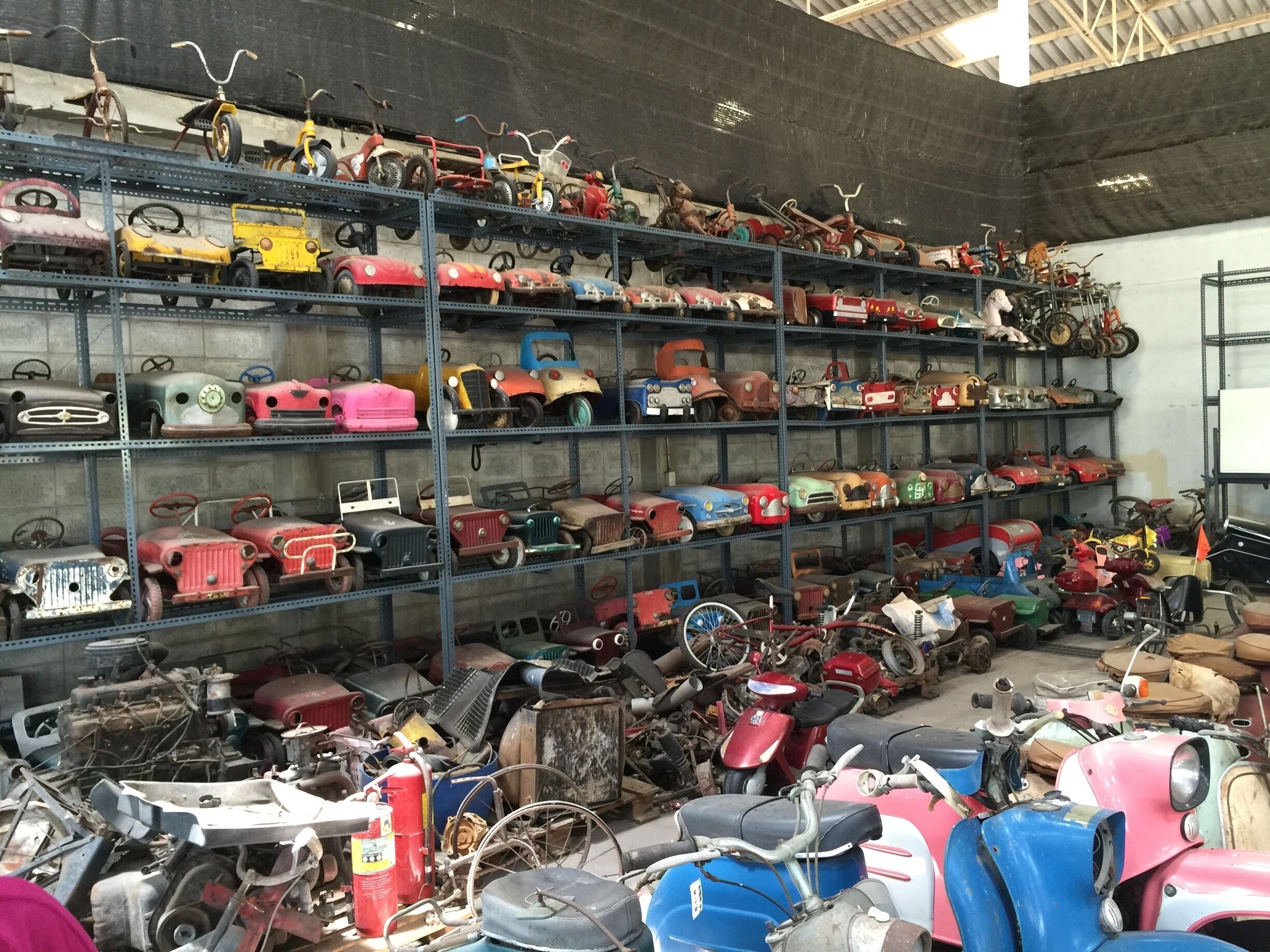 A storage room filled with various vintage toy vehicles on shelves and the floor.