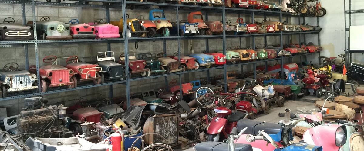 A storage room filled with various vintage toy vehicles on shelves and the floor.