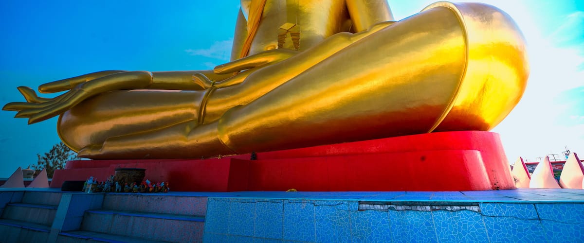 A large golden Buddha statue seated in a meditative pose on a red pedestal.